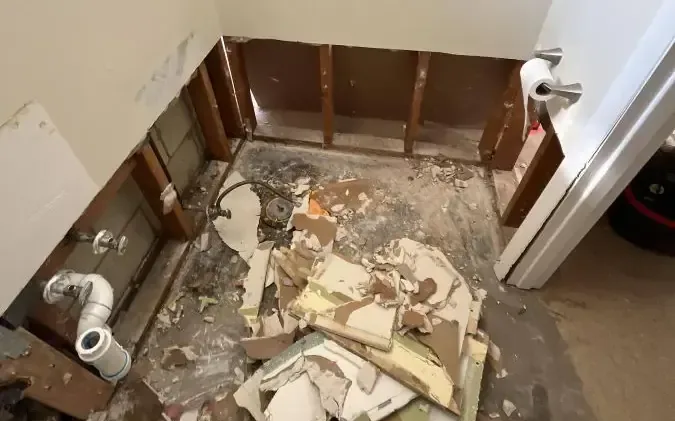 Bathroom wall framing and damaged flooring exposed during cleanup