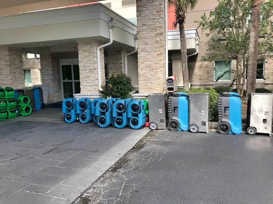 Air movers and dehumidifiers are staged outside a building entrance