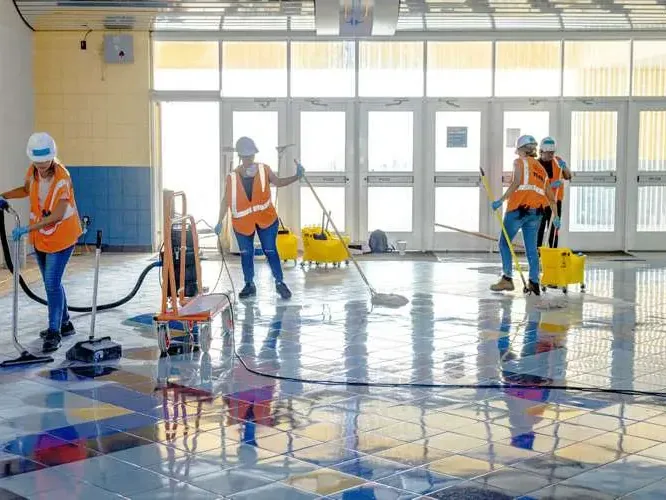 Workers push extraction tools across a flooded tile floor
