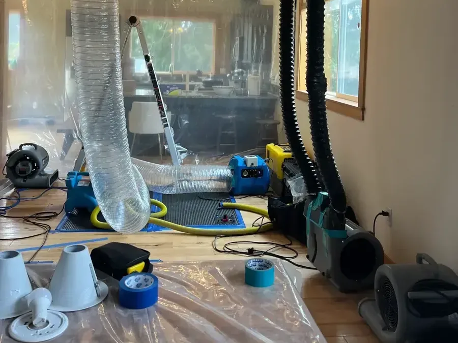 Plastic containment and drying hoses divide a room during water cleanup