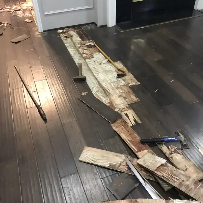 Removed wood boards expose the subfloor beside intact flooring